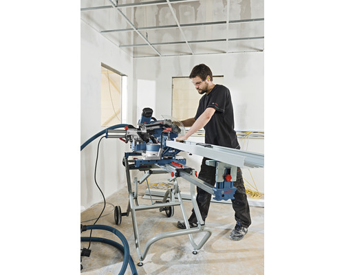 Een man werkt met een verstekzaag op een bouwplaats om een werkstuk te zagen.