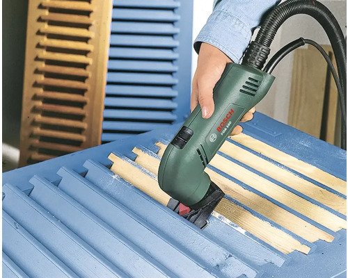 Een persoon gebruikt een elektrische schraper van Bosch om een luik te schuren.