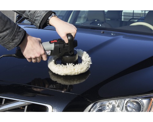 Een man polijst met een polijstmachine de motorkap van een auto.