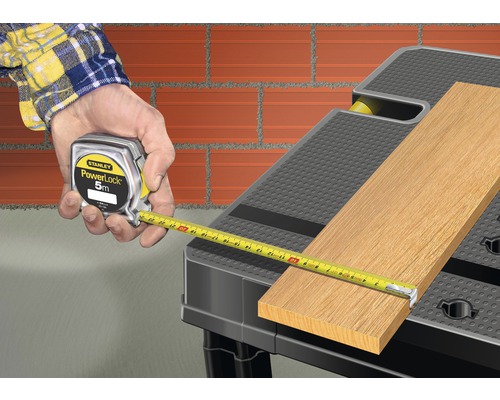 Ambachtsman meet hout met een Stanley PowerLock meetlint op een werkbank.