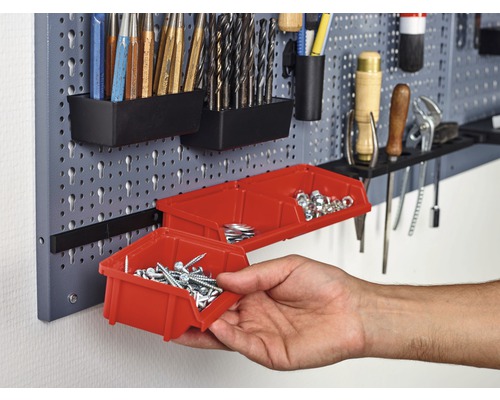 Gereedschapswand met diverse gereedschappen en rode opbergboxen