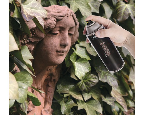 Een hand spuit met een roesteffect spuitverf op een stenen standbeeld tegen een achtergrond van klimop.