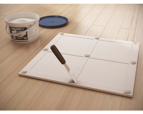 Decofit lijmemmer, plamuurmes en paneel op houten vloer