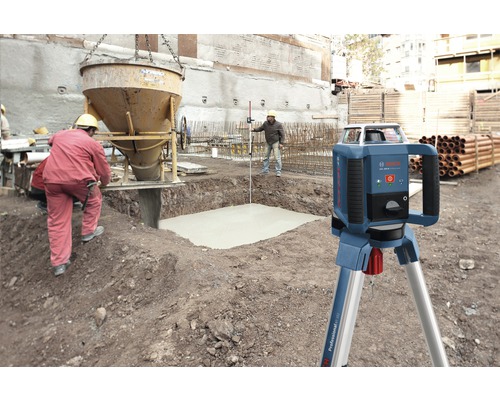 Rotatielaser op bouwplaats met betonwerkzaamheden en bouwvakkers