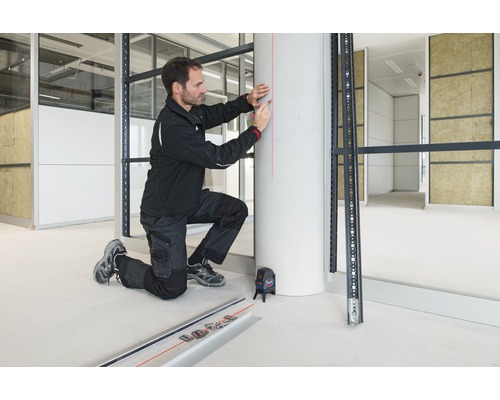 Ambachtsman met kruislijnlaser bij de montage van een metalen onderconstructie in de interieurbouw.