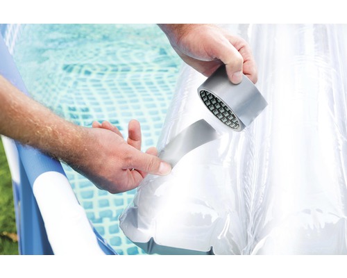 Een persoon repareert een zwembadfolie met ducttape.