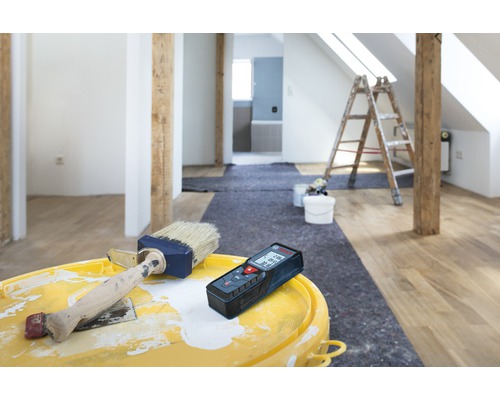 Kamerrenovatie met laser afstandsmeter, verf en penseel op een emmer