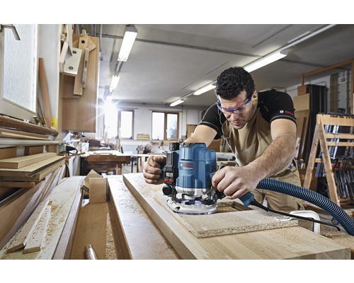 Ambachtsman gebruikt een bovenfrees van Bosch in een houtbewerkingswerkplaats.