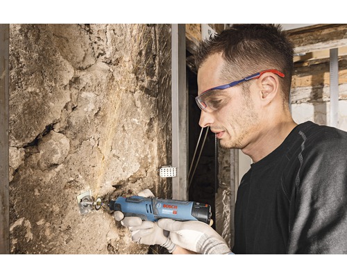 Man werkt met een multifunctioneel gereedschap aan een stenen muur