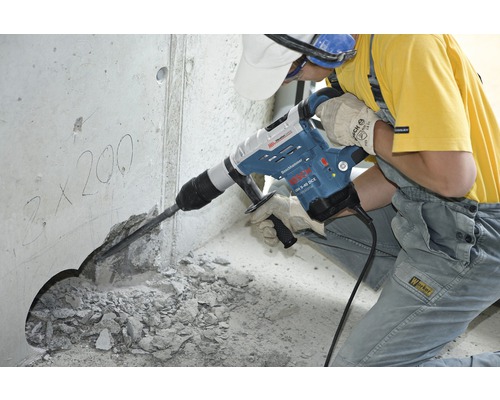 Een bouwvakker gebruikt een boorhamer om een gat in een betonnen muur te boren.