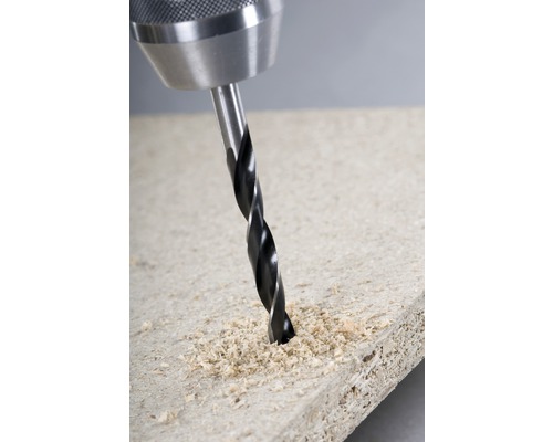 Een boormachine boort een gat in een houten plank.