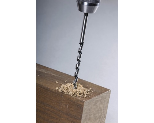 Houtboor in gebruik op een stuk hout met houtsnippers