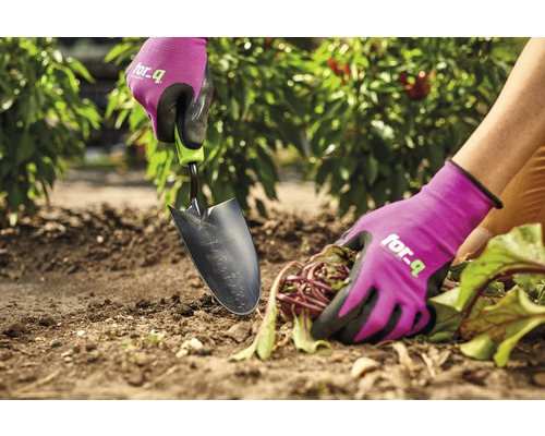 Close-up van een persoon die met een tuinschep en tuinhandschoenen in de tuin werkt