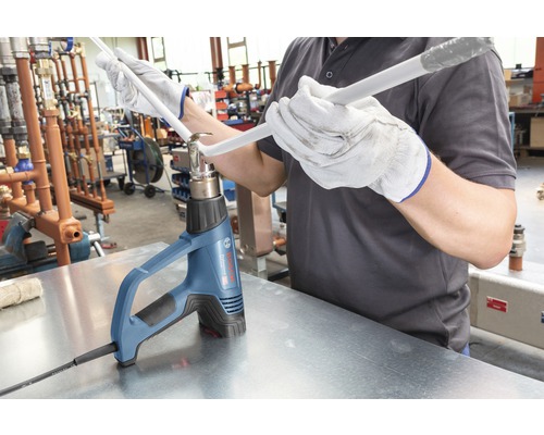 Ambachtsman buigt een plastic buis met een heteluchtpistool.