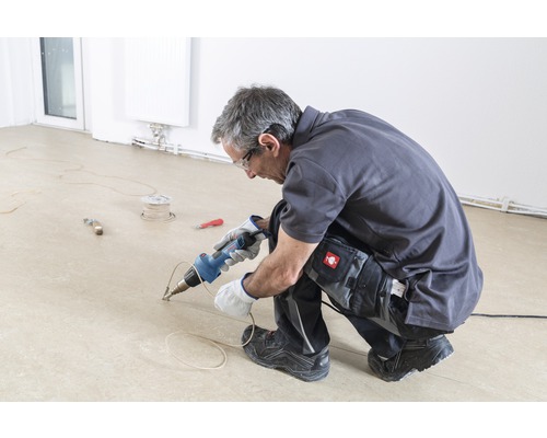 Een vakman last een vloer met een lasapparaat.