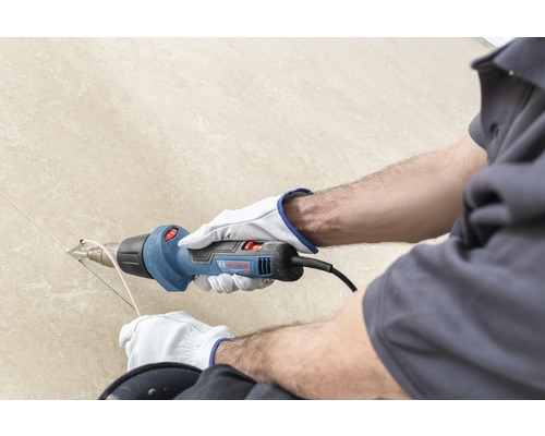 Ambachtsman gebruikt een heteluchtpistool van Bosch voor installatiewerkzaamheden