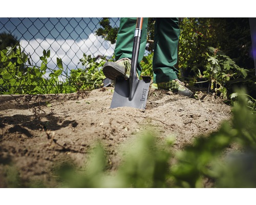 Tuinscène met een persoon die een spade in de grond steekt