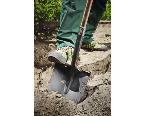 Een persoon gebruikt een spade om in de tuin te graven.