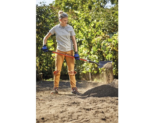 Een vrouw schept aarde met een spade in een tuin.