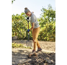 Een vrouw werkt met een greep in de tuin.
