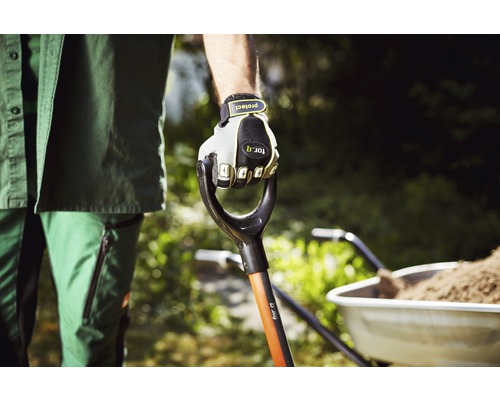 Tuinman houdt spade vast met handschoenen aan, kruiwagen op de achtergrond