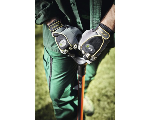 Een persoon in werkkleding houdt een spade vast met tuinhandschoenen.