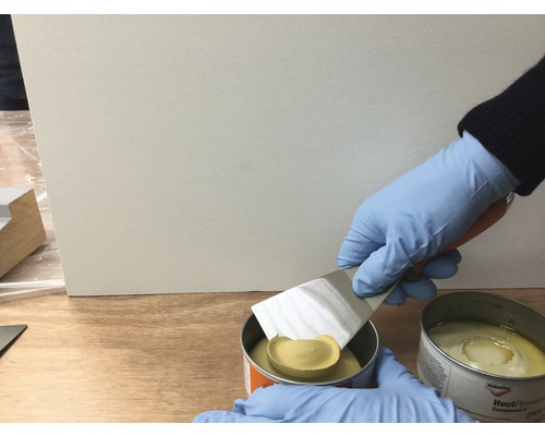 Persoon mengt houtreparatiemassa met plamuurmes