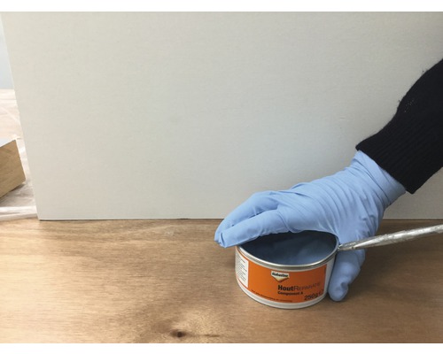 Blik houtreparatieplamuur met hand en penseel