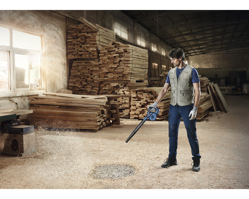 Man maakt werkplaats schoon met een bladblazer voor houtsnippers.
