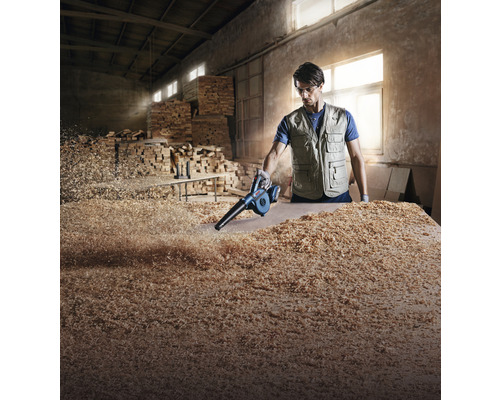 Man maakt werkbank schoon met bladblazer van houtsnippers