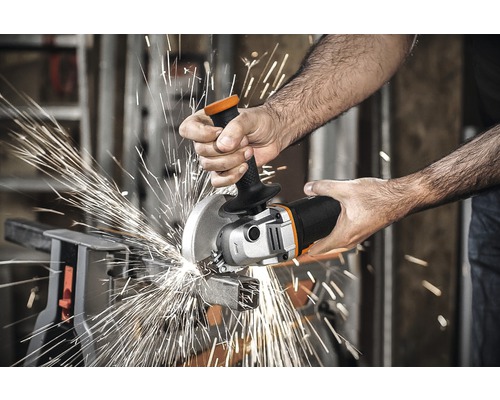 Een persoon snijdt met een haakse slijper een stuk metaal, waarbij vonken vliegen.
