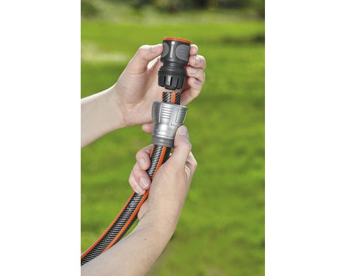 Twee handen verbinden een tuinslang met een koppelstuk.