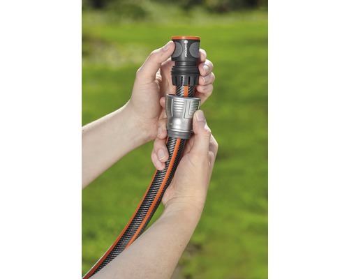 Twee handen verbinden een tuinslang met een slangconnector.