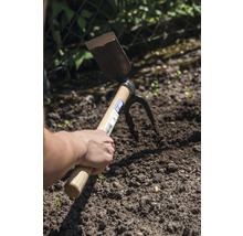 Hand houdt een dubbele functie schoffel in de tuingrond
