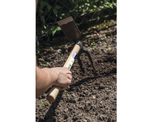 Hand houdt een dubbele functie schoffel in de tuingrond