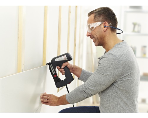 Man bevestigt wandpanelen met een elektrische tacker aan een wand