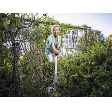 Vrouw gebruikt een worteltrekker in de tuin om onkruid te verwijderen