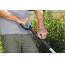Close-up van een persoon die een gazonbeluchter of verticuteermachine met handgreep bedient, voor tuinonderhoud