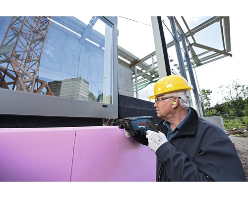 Vakman snijdt met een reciprozaag een isolatieplaat op een gebouw.