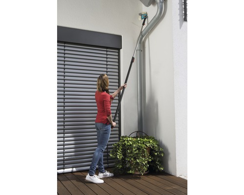 Vrouw reinigt dakgoot met telescoopsteelgereedschap voor rolluik