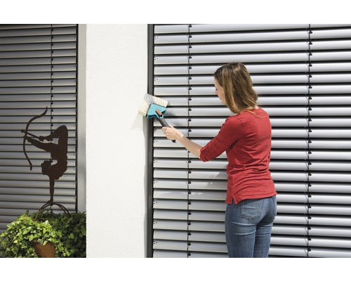 Vrouw reinigt jaloezieën met een borstel.