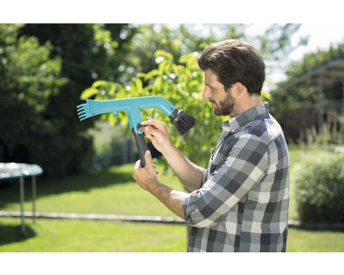 Man bedient een dakgootborstel in de tuin.