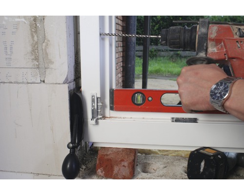 Een raam wordt geïnstalleerd met een boormachine en een waterpas.