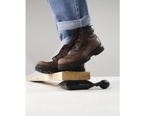 Persoon met laarzen balanceert op luchtkussen tussen stukken hout