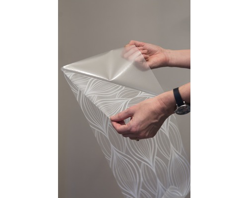 Een rol behang met patroon wordt vastgehouden door twee handen.