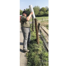 Een persoon plaatst een afdekking op een houten hekpaal buitenshuis. Hekwerkconstructie.