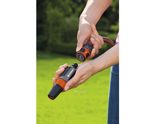 Handen verbinden een Gardena slangstuk met een slangconnector