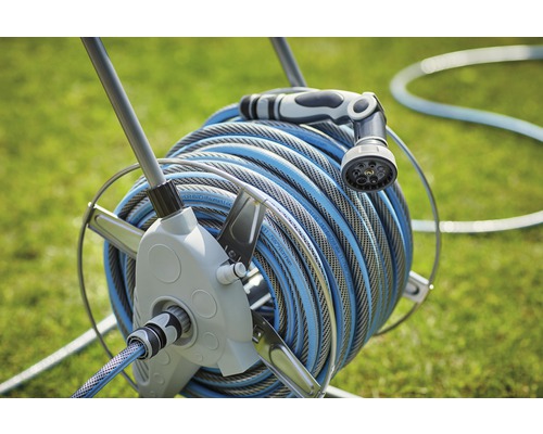 Oproller met tuinslang en spuitmondstuk in de tuin