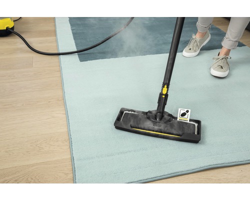 Een persoon reinigt een tapijt met een stoomreiniger.