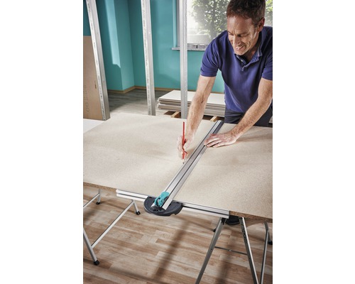 Een man markeert met een potlood een gipsplaat met een snijgereedschap op een tafel